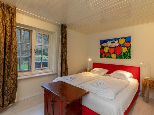 - une chambre avec un lit rouge et une fenêtre dans l'établissement Charming thatched beach villa with garden, à Biggekerke