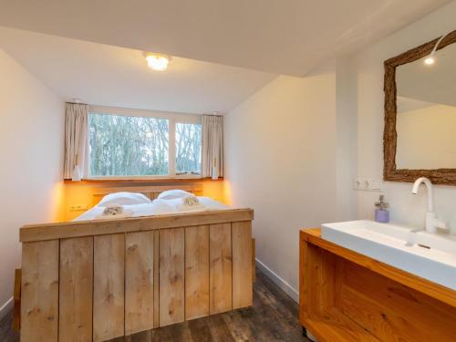 La salle de bains est pourvue d'une baignoire en bois et d'un lavabo. dans l'établissement Charming thatched beach villa with garden, à Biggekerke