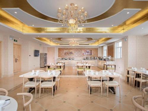 Laiwu的住宿－Vienna Hotel Jinan Laiwu General Bus Station，一间配备有白色桌椅和吊灯的餐厅