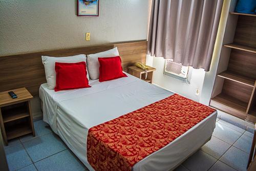 um quarto de hotel com uma cama com almofadas vermelhas em Plaza Hotel São José dos Campos em São José dos Campos