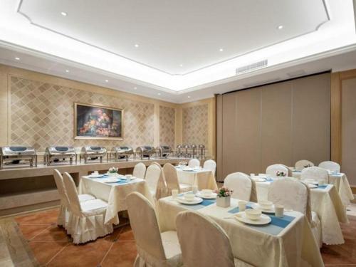 uma sala de conferências com mesas e cadeiras brancas e um ecrã em Vienna Hotel Chongqing Lijiatuo Pedestrian Street em Nanwenquan