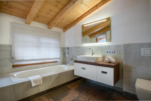 a bathroom with a tub and a sink and a toilet at Ski & Golf Auszeit Apartment by Alpine Host Helpers in Kitzbühel