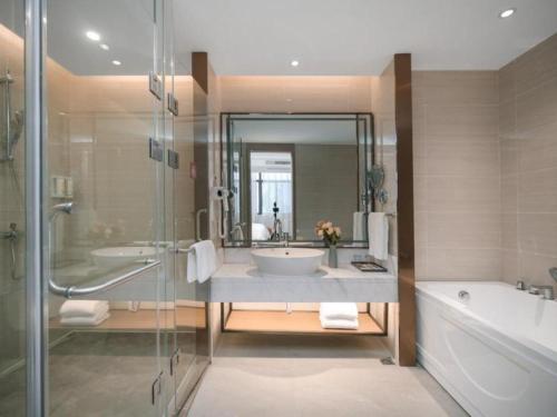 a bathroom with a tub and a sink and a shower at Vienna Hotel Wuhu Ruifeng Shangbo City in Wuhu