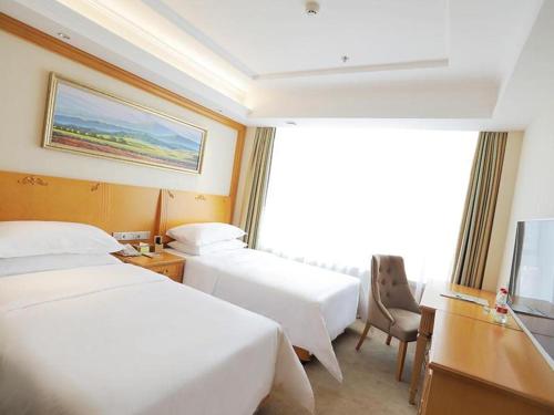 een hotelkamer met 2 bedden, een bureau en een televisie bij Vienna Hotel Shenyang Central Street in Shenyang