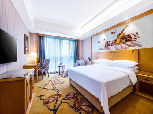 Cette chambre comprend un grand lit et une télévision à écran plat. dans l'établissement Vienna Hotel Hunan Yueyang Linxiang, à Linxiang