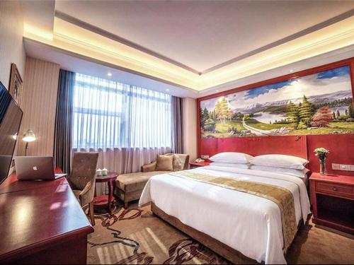 a hotel room with a large bed and a desk at Vienna Hotel Hebei Qinhuangdao Hebei Street Taiyangcheng in Qinhuangdao