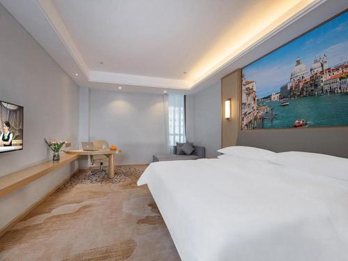 ein großes weißes Schlafzimmer mit einem großen Gemälde an der Wand in der Unterkunft Vienna Hotel Fuzhou Mawei in Mawei