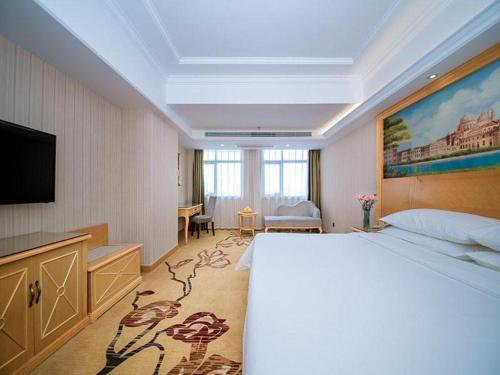 a hotel room with a bed and a flat screen tv at Vienna Hotel Hubei Xiangyang Tang City Gulou in Xiangyang