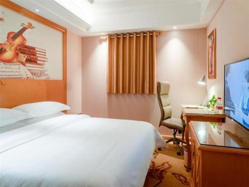 a hotel room with a bed and a desk and a television at Vienna Hotel Jiangsu Kunshan Changjiang North Road Fenghuangcheng in Kunshan