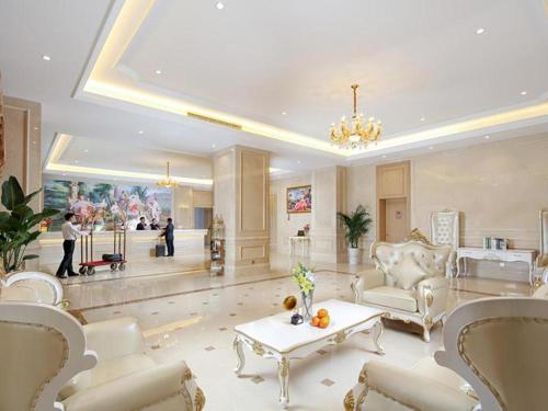 ein großes Wohnzimmer mit weißen Möbeln und einem Kronleuchter in der Unterkunft Vienna Hotel Baoshan Yongchang Road in Baoshan