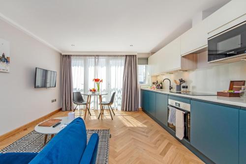 Farringdon Serviced Apartments في لندن: مطبخ وغرفة معيشة مع أريكة زرقاء
