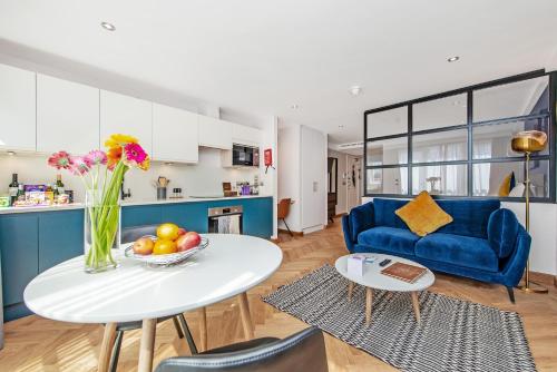 a living room with a table and a blue couch at Farringdon Serviced Apartments by LovelyStay in London