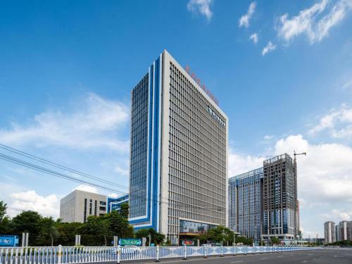 a tall glass building in a city with a street at Venus Royal Hotel Nanning East High-Speed Railway Station in Nanning