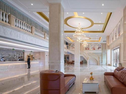 eine Lobby mit einem Kronleuchter und einer Person in einem Gebäude in der Unterkunft Vienna Hotel Guangdong Chaozhou Chaoshan High-Speed Railway Station in Denggang