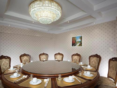 comedor con mesa, sillas y lámpara de araña en Vienna Hotel Hohhot Zhaojun Road en Hohhot