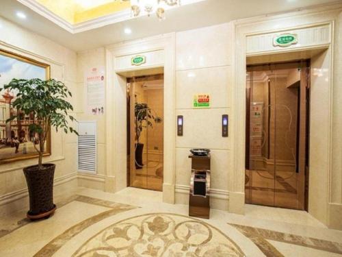 a lobby with two elevators and a potted plant at Vienna Hotel Qinghai Xining Deling Halu City East Wanda Plaza in Xining