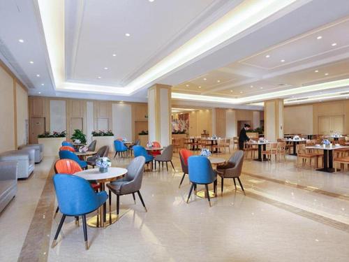 a restaurant with tables and chairs in a room at Vienna Hotel Wuhan Erqi Changjiang Bridge Yujiatou in Jiang'an