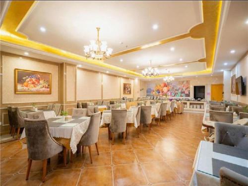 un ristorante con tavoli e sedie in una stanza di Vienna Hotel Tianjin Zhongbei Town a Caozhuang