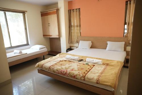 ein Schlafzimmer mit einem großen Bett und zwei Fenstern in der Unterkunft HOTEL SAI SURYA in Shirdi