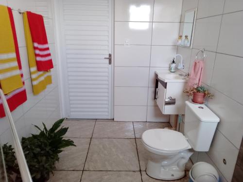 a white bathroom with a toilet and a sink at Chácara a 6km do centro! in Poços de Caldas