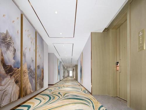 a long hallway with paintings on the walls at Venus Royal Hotel Guangxi Wuzhou Sanqicheng Meiguihu Park in Wuzhou