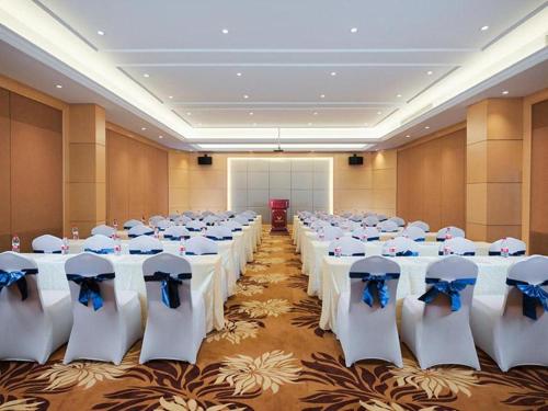 einen Bankettsaal mit weißen Tischen und Stühlen mit blauen Bogen in der Unterkunft Vienna Hotel Jiangxi Jiujiang Gongqingcheng High-Speed Railway Station in Gongqingcheng