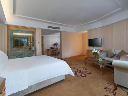 ein großes Schlafzimmer mit einem großen Bett und einem Sofa in der Unterkunft Vienna Hotel Jiangxi Jiujiang Gongqingcheng High-Speed Railway Station in Gongqingcheng