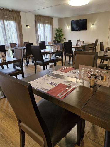 a dining room with tables and chairs and a television at Hôtel Inn Design - Restaurant L'Escale in Rochefort