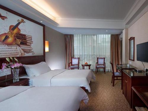 Cette chambre comprend deux lits et une télévision. dans l'établissement Vienna Hotel Guangxi Fusui, 