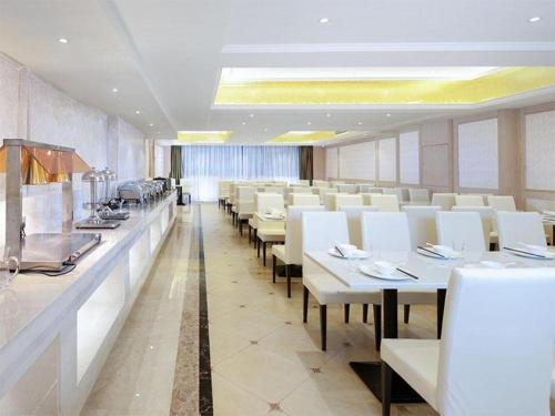 un comedor con mesas blancas y sillas blancas en Vienna Hotel Guangxi Fusui, 