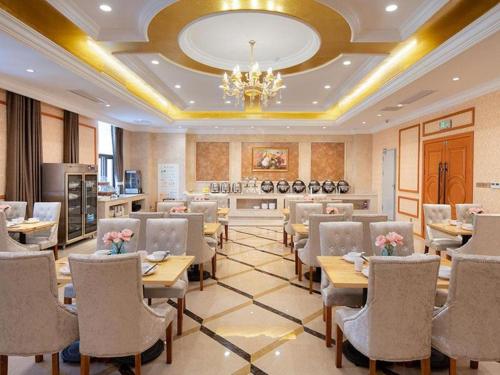 un restaurante con mesas y sillas y una lámpara de araña en Vienna Hotel Anhui Bengbu Guzhen Railway Station en Qiaokou