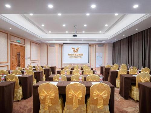 una sala de conferencias con mesas, sillas y una pantalla en Vienna Hotel Anhui Bengbu Guzhen Railway Station en Qiaokou