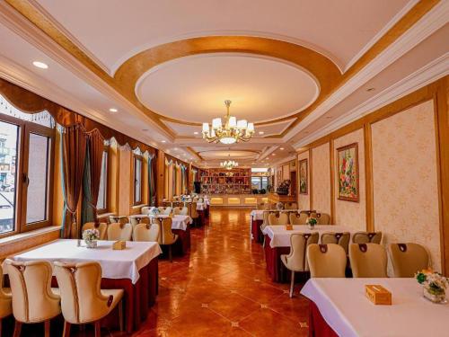 a restaurant with tables and chairs and a chandelier at Vienna Hotel Heilongjiang Qiqihar South Road in Qiqihar