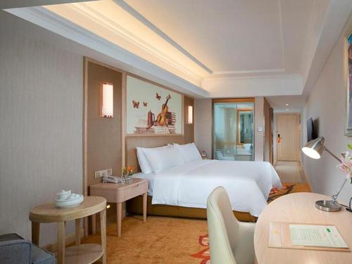une chambre avec un grand lit blanc et un salon dans l'établissement Vienna Hotel Guangdong Chaozhou Fenghuang New City, 