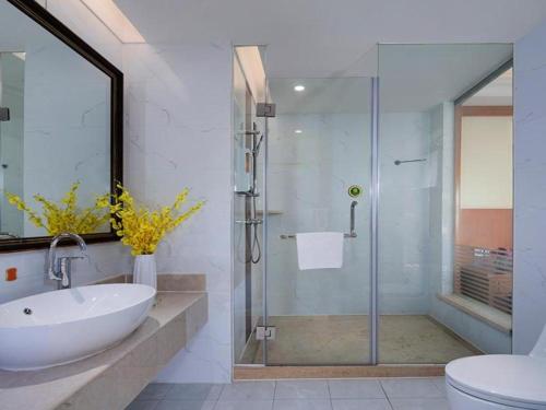 W łazience znajduje się umywalka i przeszklony prysznic. w obiekcie Vienna Hotel Shanxi Datong High-Speed Railway Station Wanda Plaza w mieście Shaling