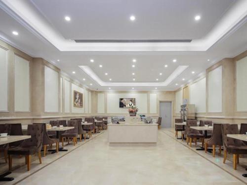 合肥市にあるVienna Hotel Hefei Railway Station Yuanyi Times Plazaのテーブルと椅子付きの広いダイニングルーム