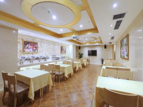 un restaurante con mesas y sillas blancas y un bar en Vienna Hotel Chongqing Jiefangbei Hongyadong, en Chongqing