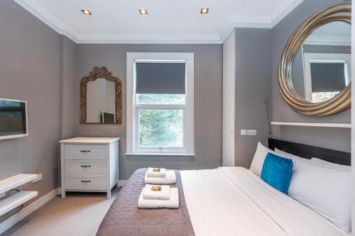 a bedroom with a large bed and a mirror at Luxury 1BR, 2 min Putney Train St, 5 min to Tube in London