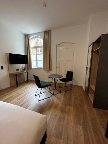 a room with a table and chairs and a bed at Hopfenhotel am Adenauerufer in Bamberg