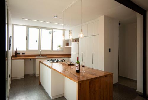 a kitchen with white cabinets and a wooden counter top at La Puerta Amarilla in Mendoza