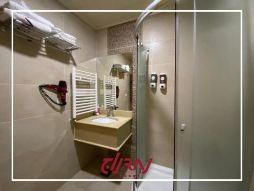 W łazience znajduje się umywalka i lustro. w obiekcie Raj Hotel w mieście Alajh