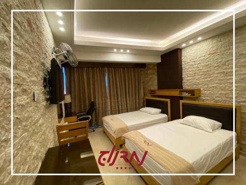 Pokój z 2 łóżkami, biurkiem i pokojem w obiekcie Raj Hotel w mieście Alajh