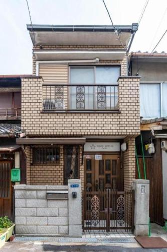 a brick house with a gate and a balcony at Bijou Suites Will in Osaka
