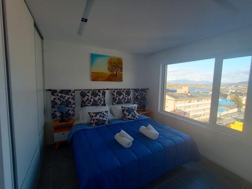 1 dormitorio con cama azul y ventana grande en Rincon del Beagle en Ushuaia