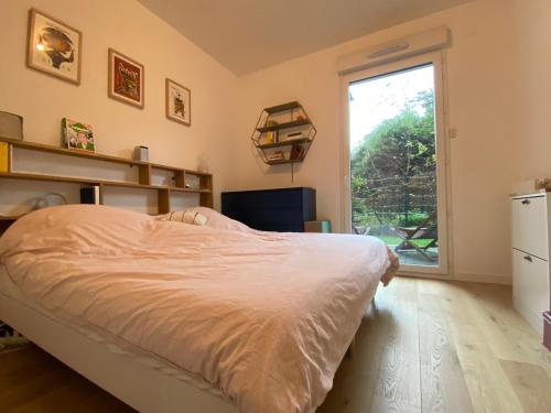 um quarto com uma cama e uma grande janela em Le jardin de Clémentine & Julien em Saint-Ouen