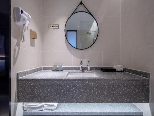 a bathroom with a sink and a mirror at Borrman Hotel Wuzhou College Fumin Road in Wuzhou