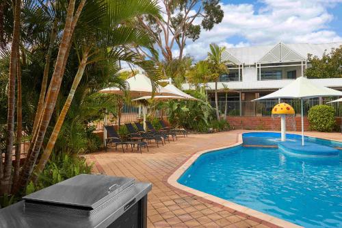 una casa y una piscina con sillas y sombrillas en Broadwater Resort Como, en Perth
