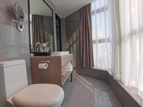 uma casa de banho com um WC, um lavatório e um espelho. em GreenTree Eastern Hotel Chongqing Xiejiawan Light Rail Station em Jiulongpo