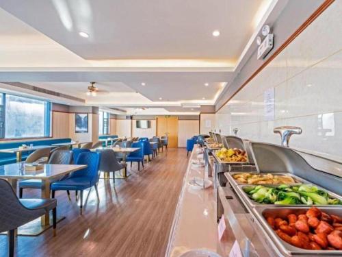un restaurante con una línea de buffet con mesas y sillas en Gya Hotel Zhuhai International Airport New Town en Baigaonongchang