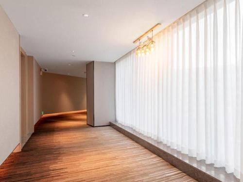 un pasillo con una gran ventana con persianas blancas en Gya Hotel Zhuhai International Airport New Town en Baigaonongchang